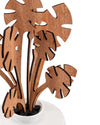 Brown wooden decorative plant by Alessi, featuring black-edged abstract monstera leaves in a white ceramic pot.