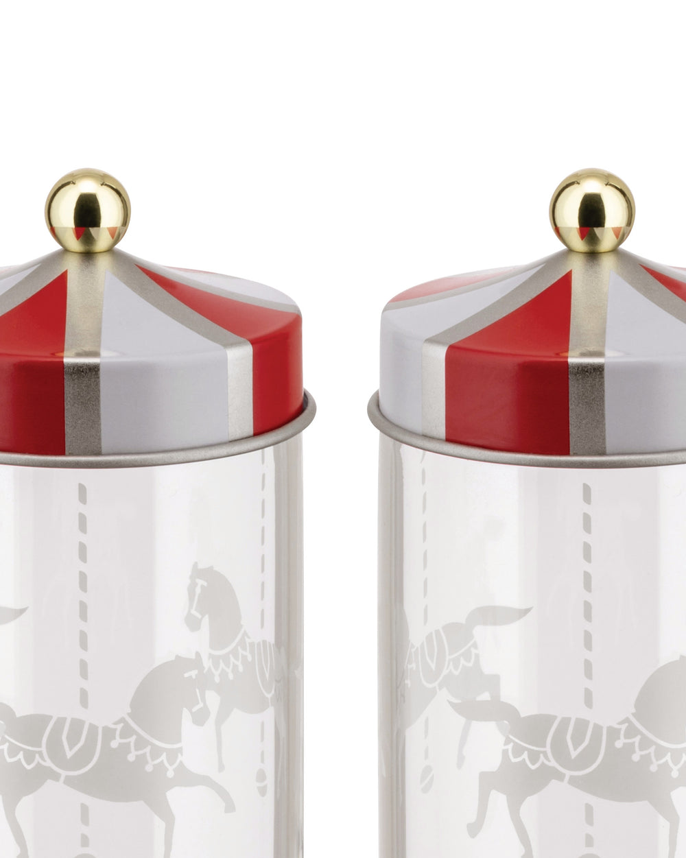 Two carousel-themed jars by Alessi with red and white striped lids, golden ball finials, and frosted horse patterns.