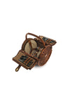 Brown woven wicker picnic basket by Alessi, open with beige plates, glasses, and black cutlery inside.
