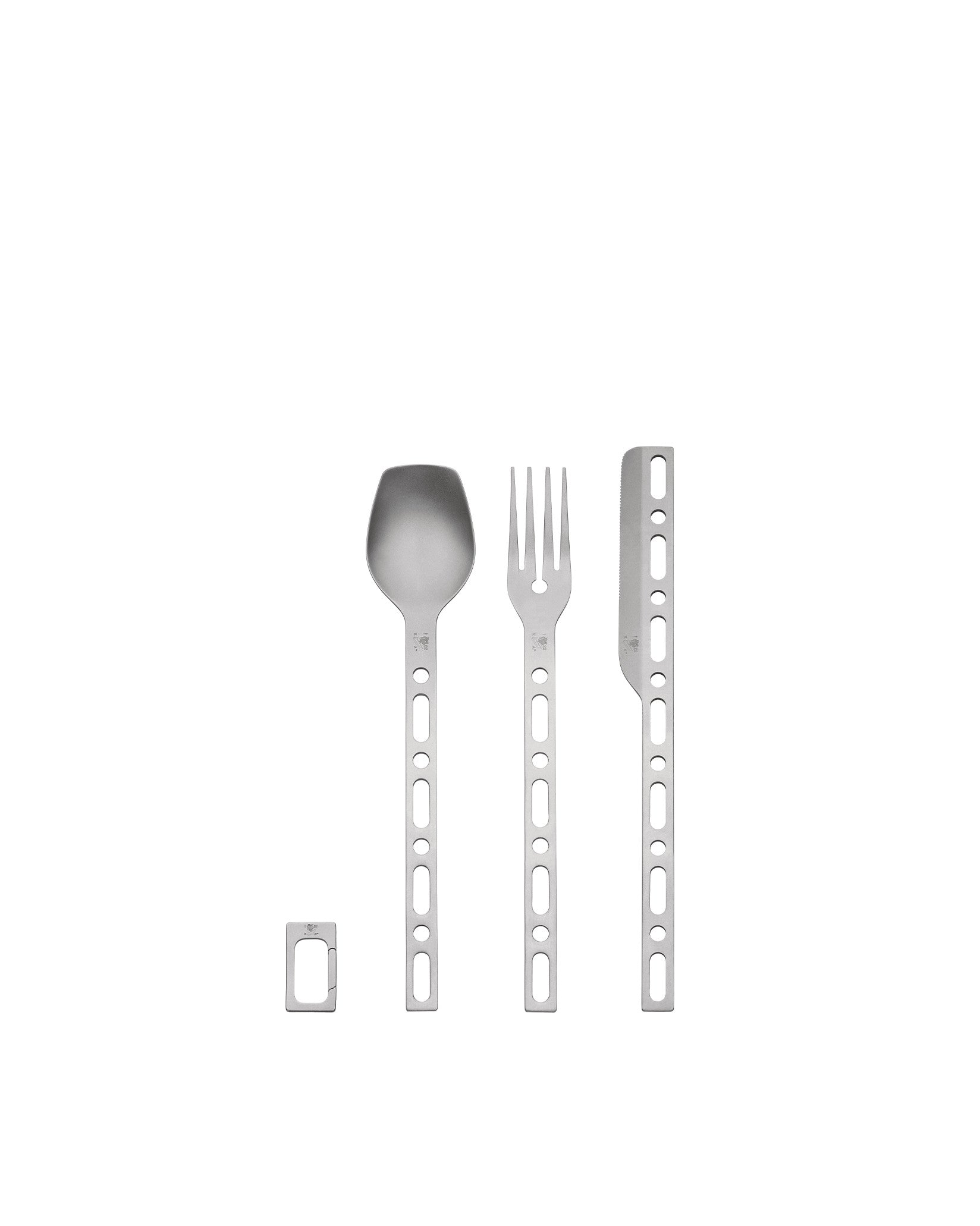 Silver flatware set by Alessi, featuring a spoon, fork, knife, and clip with circular handle cutouts.