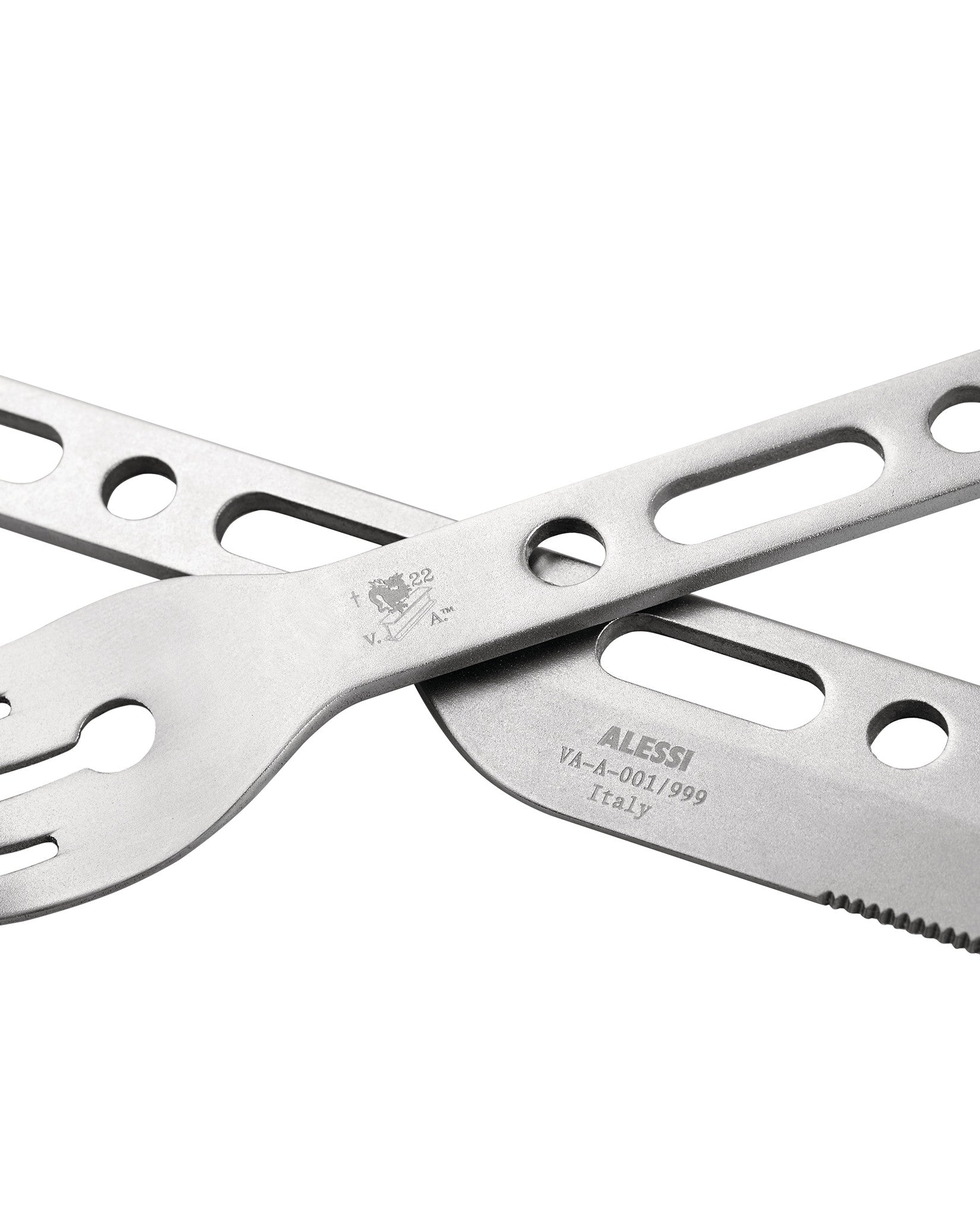 Silver metallic multi-tool cutlery by Alessi, featuring a serrated knife and fork, in a close-up.