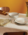 Polished silver cutlery set by Alessi, including spoons, forks, and knives displayed on a light green napkin.