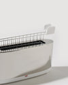 Polished stainless steel toaster by Alessi with a single long slot and a white removable warming rack.