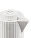 White electric kettle by Alessi, with a pleated body, ribbed lid, and prominent pouring spout.