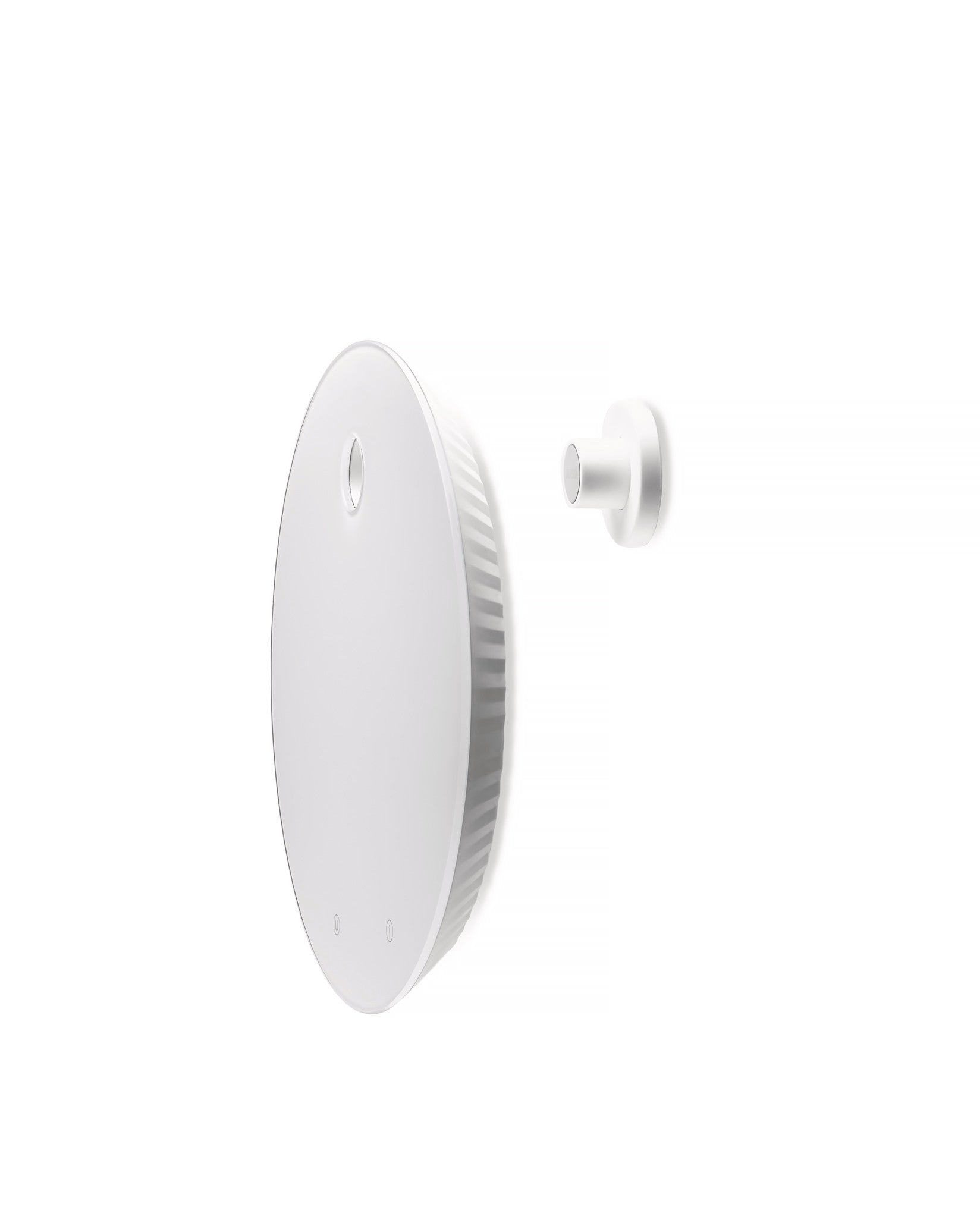 White circular kitchen scale by Alessi, with ridged sides and a small oval indentation, next to a white cylindrical wall mount.