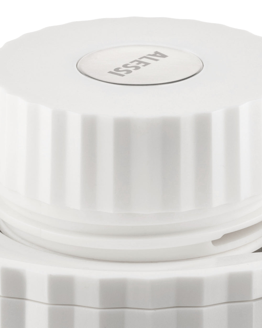 White pleated lid by Alessi with a circular metal logo, shown from an elevated angle.