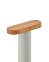 Kitchen roll holder by Alessi with an oval bamboo wood top and matte grey cylindrical base, cropped view.