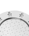 Round silver-toned metal disk by Alessi, featuring stick figure cutouts along the rim and small perforations.